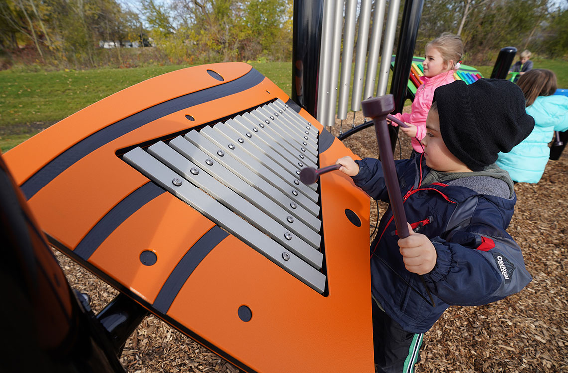 Child playing xylophone in park